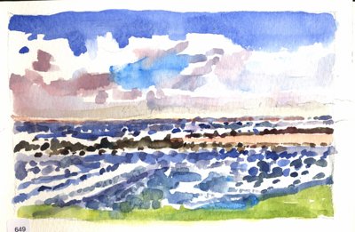 Ocean waves and rocky shoreline under a broad sky.