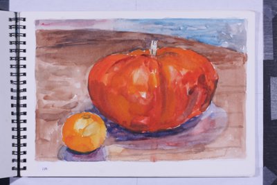 Still life with large orange pumpkin or squash and a smaller orange fruit on a tabletop.
